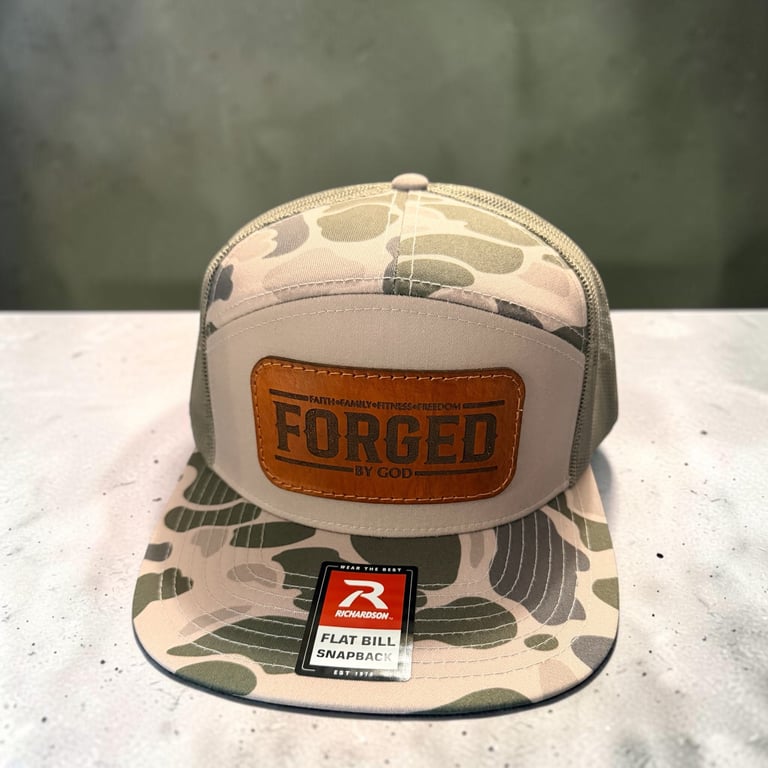 Camouflage baseball cap with white and gray patterns, orange FORGED leather patch, and flat bill snap back closure